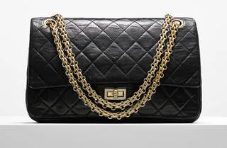 Black rectangular quilted handbag with gold metal straps and a gold fastening.