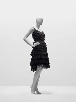 Black tiered dress made of silk chiffon and taffeta. It is sleeveless and knee-length.